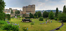 Large green area with small open sided structure in the middle. Behind is a yellow couloured building.