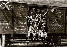 Men waving from the door and window of a rail goods van