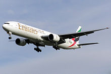 Aircraft during landing approach. Front quarter view of twin-engine jet in flight with flaps and landing gear extended.