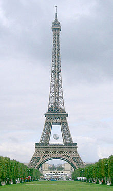 An avenue of trees leads to a large iron lattice tower, in which an oversized rugby ball hangs within the lower sections.